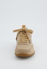 Beżowe trampki wykonane z materiałów zamszowych i skórzanych, z zasuwanym zapięciem, okrągłym czubkiem, teksturowaną podeszwą i wyściełanym językiem dla komfortu.