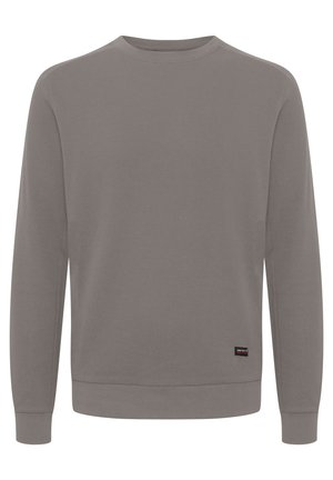 Siva majica s crewneck izrezom, izdelana iz teksturiranega pletenega materiala, dolgimi rokavi, rebrastimi manšetami in obodom ter majhno blagovno oznako na spodnjem levem robu.