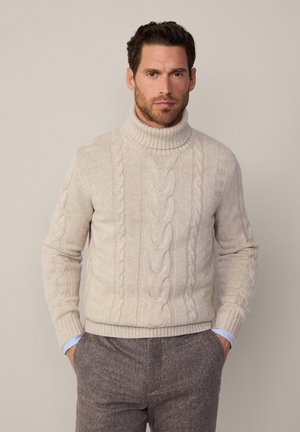 Beige Kabelstrick-Pullover mit Rollkragen, gerippten Bündchen und Saum, ausgestattet mit ausgeprägten Kabelmustern und einer strukturierten Oberfläche.