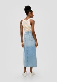 Helles blaues Denim-Maxi-Rock mit hoher Taille, Gesäßtaschen und geradem Schnitt. Kombiniert mit einem weißen Tanktop mit orangen Streifen.