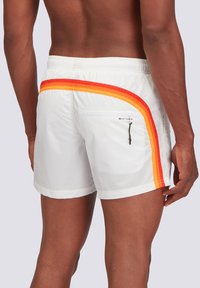 Costumi da bagno bianchi con una striscia diagonale rossa e arancione, dotati di una tasca con zip sul retro e vita elastica per una vestibilità sicura.