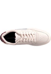Sneaker sintetica bianca con superficie testurizzata, dotata di punta arrotondata, perforazioni e accenti bordeaux sul tallone e sulla fodera.