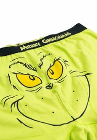 Boxer in cotone verde con una grande stampa del volto del Grinch e occhi gialli, accentuati da un elastico nero con il testo "MERRY GRINCHMAS".