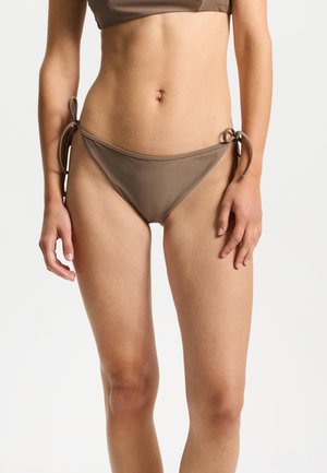 Parte inferior de bikini en marrón, hecha de tela lisa. Cuenta con laterales ajustables con lazos y una sutil marca en la cintura. Ajuste regular y cobertura mínima.