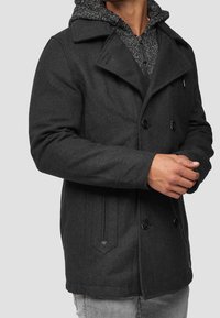 Cappotto doppiopetto color grigio scuro con cappuccio testurizzato, grandi bottoni neri e tasche laterali, caratterizzato da una vestibilità sagomata.