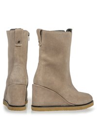 Botas de cuña de ante beige con punta redonda, textura suave y cremallera lateral. Presentan una suela negra sutil para un mejor agarre.