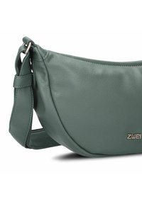 Bolso de hombro de cuero verde con superficie texturizada, correa ajustable y un sutil logo metálico. Diseño curvado con una forma suave.