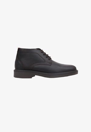 Bottine en cuir noir avec fermeture à lacets et surpiqûres marron sur une semelle en caoutchouc plate, vue de côté extérieur.