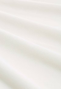 Tessuto bianco a righe con morbide pieghe diagonali e leggeri giochi di ombre che evidenziano la texture e la dolce curvatura.
