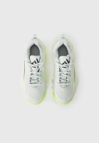 Baskets sportives gris clair avec une tige en mesh texturé, des accents noirs et une semelle vert fluo. Elles possèdent des lacets ronds et une boucle au talon pour un enfilage facile.