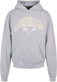 Šedá mikina s kapucňou a kloktyňou. Na prednej strane sú žlté nápisy "MJ GONZALES" a biele rukou písané akcenty.