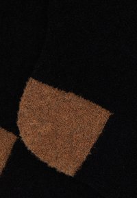 Calzini in misto lana neri con una toppa rettangolare marrone a contrasto e texture. Finitura morbida e pelosa con un design a blocchi di colore ben definito.