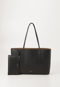 Sac fourre-tout en cuir noir avec de longues poignées et une pochette zippée assortie amovible, tous deux ornés de logos Calvin Klein discrets.