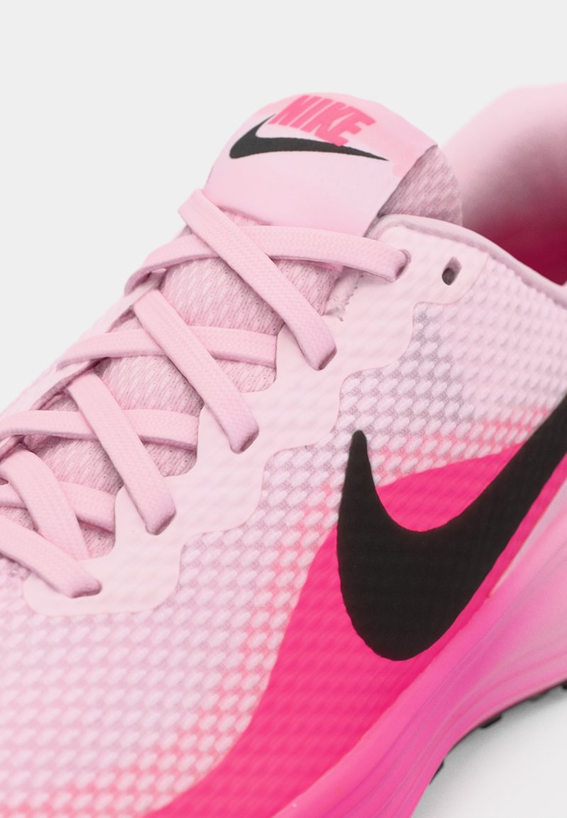 Zapatilla de running de Nike con una parte superior de malla rosa, acentos en rosa y negro, y una suela texturizada. Los cordones son rosas, con un logo negro en la lengüeta.