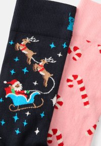 Para skarpetek: jedna granatowa z wizerunkiem Świętego Mikołaja, sanek i reniferów; druga różowa z motywami cukrowych lasek w kolorze czerwonym i białym. Miękka dzianina.