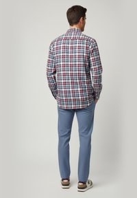 Camisa de manga larga para hombre en un patrón de cuadros azul, rojo y blanco; combinada con pantalones texturizados azul claro y zapatos casuales.
