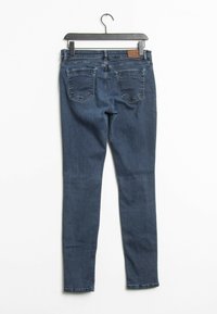 Tmavě modré skinny džíny s hladkou denimovou texturou, pěti kapsami, lehce opotřebovanými detaily a poutkem na opasek v pase.