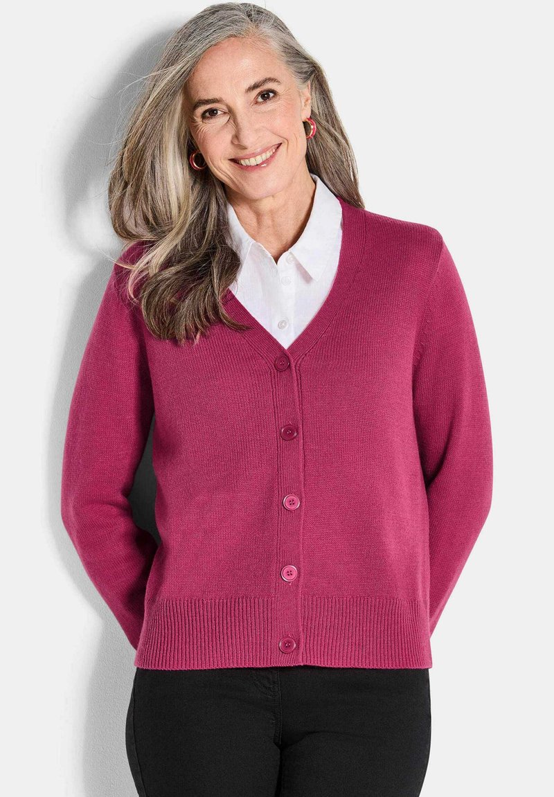 Fuchsia cardigan van zachte brei, met een V-hals, knoopsluiting, geribbelde manchetten en zoom, gecombineerd met een witte blouse met kraag.