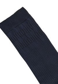 Calza blu navy a coste con polsino testurizzato, caratterizzata da un corpo liscio e linee verticali per un dettaglio aggiuntivo. Realizzata in un materiale tessile morbido.