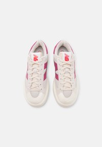 Zapatillas con un diseño ligero, con parte superior de un beige claro, acentos en rosa y paneles de malla texturizada. Suela de goma y cordones incluidos.