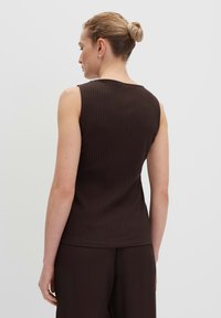 Brown ribbed sleeveless top with a round neckline. Smooth texture, fitted design. Model viewed from the back, hair styled in a bun.