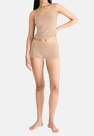Nude naadloze tanktop met brede banden, gecombineerd met bijpassende hoge taille shorts, beide gemaakt van zachte, rekbare stof.