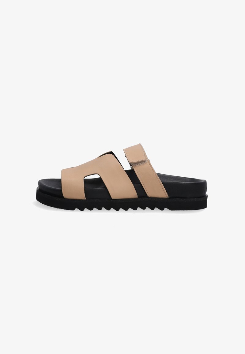 Beige lædersandal med åben tå-design, justerbar rem, sort struktureret sål og zigzag-mønster langs kanten.