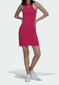 Obtažené růžové halter šaty vyrobené z měkké bavlny, s kulatým výstřihem a bílým logem jako akcentem. V kombinaci s bílými teniskami.