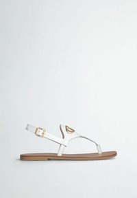 Sandali bianchi in pelle con design a infradito, cinturino alla caviglia regolabile con accessori dorati e suola piatta marrone.