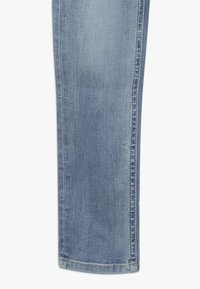 Jeans de denim azul claro con un diseño de pierna recta, que presentan una sutil textura deslavada y costuras contrastantes a lo largo de las costuras. Sin hardware visible.