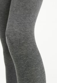 Szare, miękkie legginsy o gładkiej fakturze, z dopasowanym krojem, który modeluje sylwetkę. Minimalne szwy i jednolity kolor.