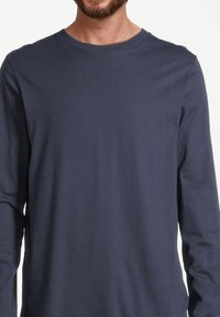 Marineblaues Langarm-T-Shirt aus weichem Baumwollmaterial, mit Rundhalsausschnitt und einer schlichten Textur ohne Muster oder Applikationen.