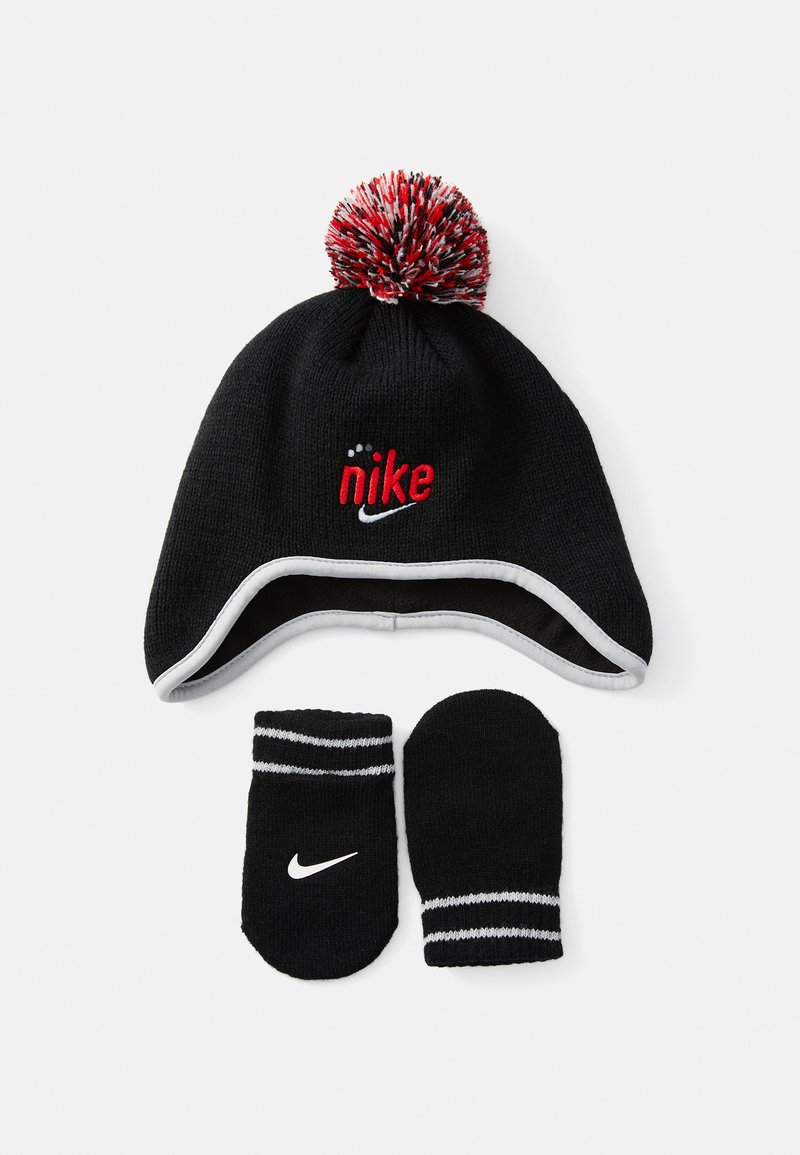 Cappello invernale Nike nero con pompon rosso e bianco e logo, abbinato a guanti neri con strisce bianche e il logo Nike bianco.