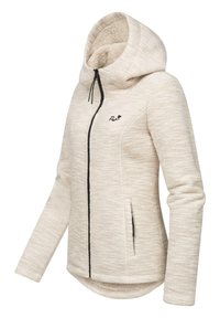 Beige huva jacka med ett strukturerat mönster, svarta dragkedjor och en mjuk, fluffig foder. Har en lätt böjd fåll och sidofickor.