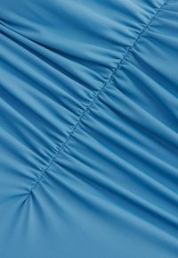 Blauer Stoff mit geraffter Textur, horizontalen Falten, glatter Oberfläche und dezentem Glanz. Das Material wirkt leicht und dehnbar.