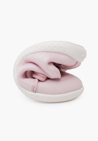 Zapato de tela suave en color rosa, con un diseño flexible, suela blanca y superficie texturizada. El zapato está enrollado de forma compacta para un almacenamiento más fácil.