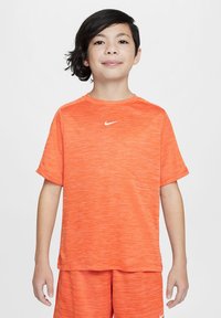 Narancssárga Nike sportfelszerelés; rövid ujjú póló, kerek nyakkivágással és textúrált anyaggal, párosítva az azonos színű sorttal. Fehér logó kiemelés.