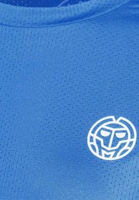 Maglietta sportiva blu con piccole perforazioni e un logo stilizzato di un volto di leone bianco sul lato destro in basso della maglia.