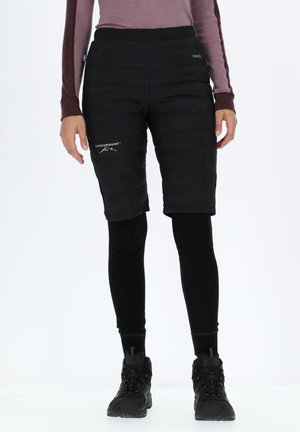 Black insulated shorts with a padded texture, featuring a logo. Paired with fitted black leggings and black footwear.