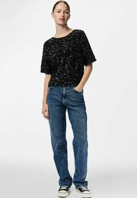 Svart paljett skjorte med korte ermer, avslappet passform, kombinert med lyseblå rette jeans og svarte lave sneakers.
