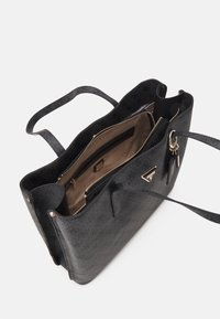 Musta rakenteellinen olkalaukku, jossa on teksturoitu pinta, nahkahandles ja kultasävytteiset yksityiskohdat. Sisäpuolella on taskuja ja vetoketjullinen osasto.