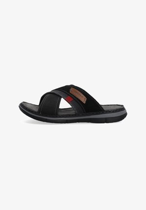 Black sandal with cross straps in textured material, featuring red accent and a tan logo patch. Durable sole with a subtle tread pattern.