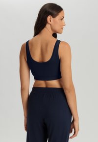 Marineblå crop top med brede stropper, rund halsudskæring og ribbet kant, lavet af et blødt, strækbart materiale for komfort.