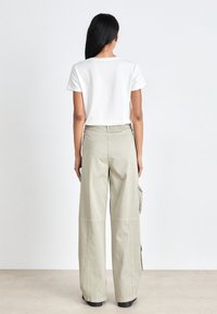 Cotton white t-shirt with short sleeves paired with loose-fitting, light gray cargo pants featuring side pockets and a straight cut.