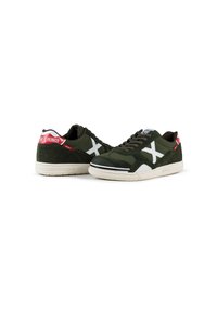 Olivengrønne sneakers med hvide krydsdetaljer, tekstureret ruskind og stof, gummisål samt røde og blå brandingdetaljer på hælene.
