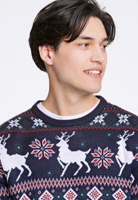 Suéter de malha azul marinho com padrão de renas brancas e flocos de neve coloridos. Gola redonda canelada com punhos e barra em contraste.