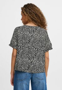 Top a maniche corte in stampa nera e crema con motivi a diamante, vestibilità morbida, scollo rotondo e finitura in tessuto soffice. Vista posteriore mostrata.