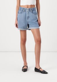 Jeanshorts med ljusblå tvätt, elastisk midja, uppvikt nederkant och framfickor, tillsammans med svarta ballerinas med silverdetaljer.