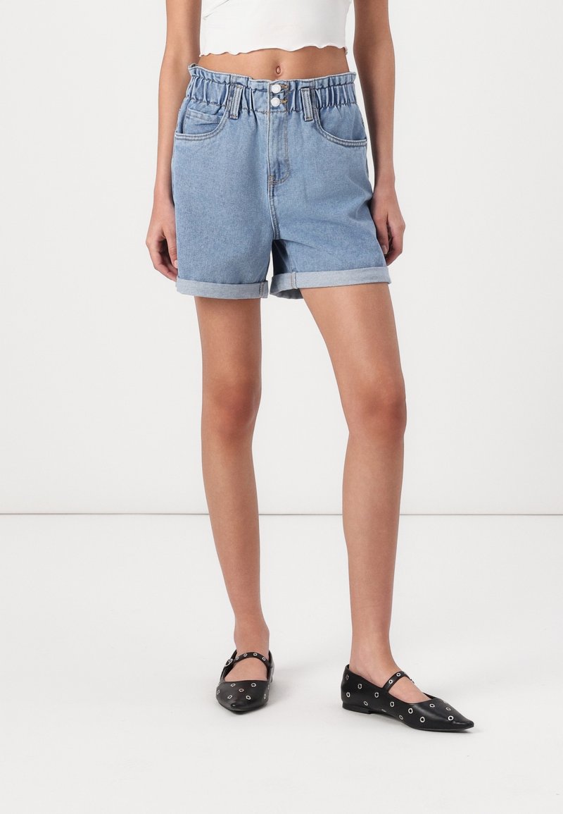 Jeanshorts med ljusblå tvätt, elastisk midja, uppvikt nederkant och framfickor, tillsammans med svarta ballerinas med silverdetaljer.