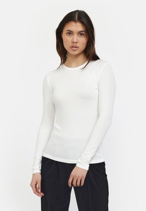 Witte lange mouw ribgebreide fitted top met een ronde halslijn, een gladde textuur en zachte stof, gecombineerd met zwarte loszittende broek.
